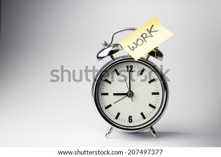 Alarm clock with sticky paper note WORK time on white background