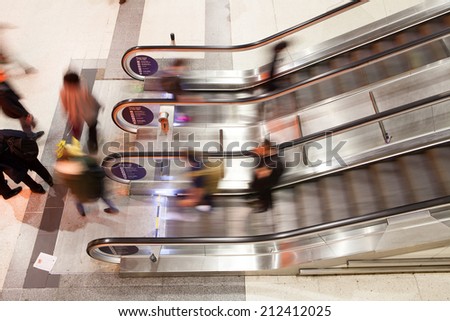 Blur Movement Business people walking on escalator in Rush Hour train station, London, UK
