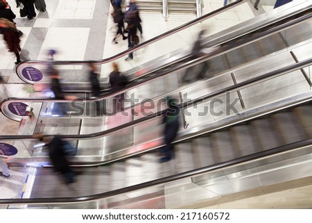 Blur Movement Business people walking on escalator in Rush Hour train station, London, UK