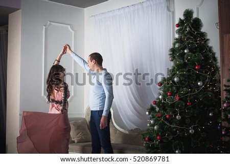 Beautiful couple celebrating Christmas. Lovers celebrate the New Year at home. Dance in a slow dance.
