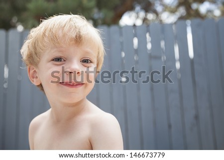 Smiling shirtless preschool age boy having fun in the summer sun with Blond Hair and copy space
