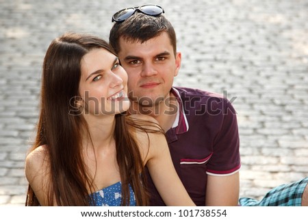 Love story of young couple on stone paving hug in summer city