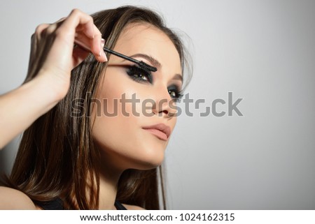Young beautiful model applying makeup. Fashion girl with mascara. Eyelash makeup.