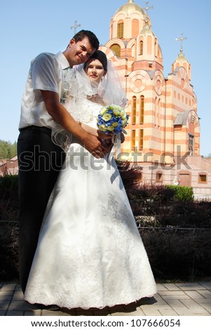 happy beautiful young bride with groom near church