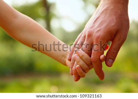 father\'s hand lead his child son in summer forest nature outdoor, trust family concept