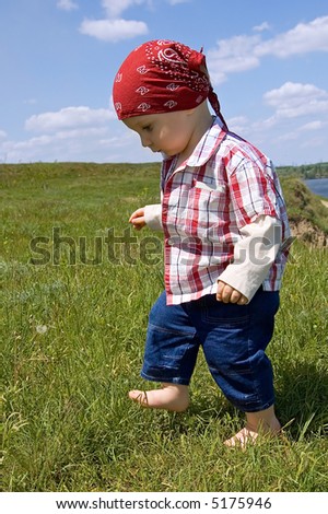 1,5 years old barefooted baby boy to step out briskly against summer landscape