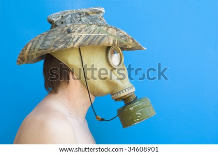 funny portrait of man with gas mask and hat against blue background