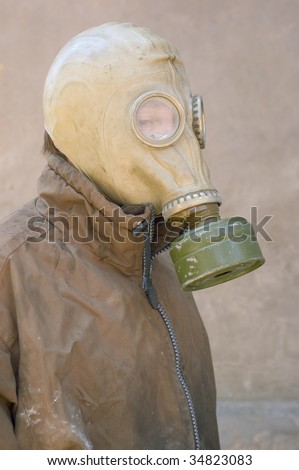 man in gas mask and dirty uniform against concrete wall