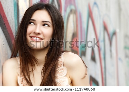 Portrait of smiling beautiful fashion girl against wall with abstract graffiti