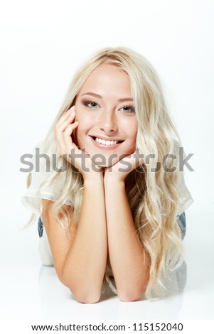 Beautiful blond teen girl lying, looking at camera and happy smiling. Isolated on white background