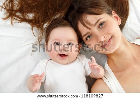 happy young mother with cute smiling baby lying in bed