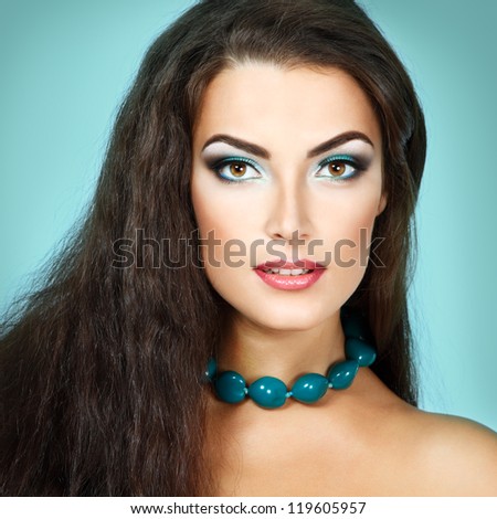 Beauty portrait of beautiful young fresh woman with long brown healthy hair. Over turquoise background