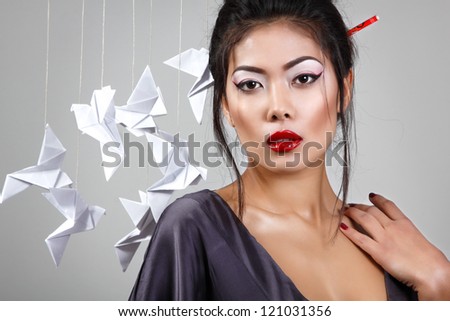Young beautiful asian woman with origami paper pigeons, studio shot