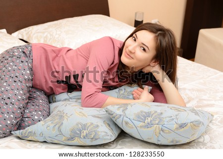 attractive cheerful teen girl in pajamas lying in her bedroom