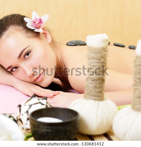 Beautiful young woman enjoy getting hot stone massage in spa salon. Beauty treatment concept, caucasian beauty model