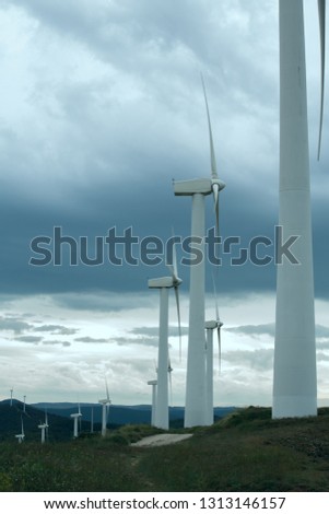 Wind turbines. Wind generators. Wind turbine generators. Alternative energy. Windmills over dramatic cloudy sky. Industrial landscape. Windmill generator. Vertical wind turbines