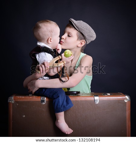 vintage art portrait of little boy hugs and kiss his baby brother leaning on old suitcase, retro stylization of 30-50s