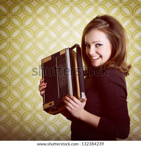 art portrait of young smiling ecstatic woman holding radio player in room with vintage wallpaper, retro stylization 60-70s, toned
