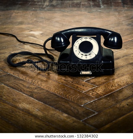 vintage old telephone, black retro phone is on the floor of used parquet
