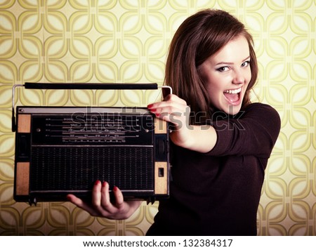 art portrait of young smiling ecstatic woman holding radio player in room with vintage wallpaper, retro stylization 60-70s, toned