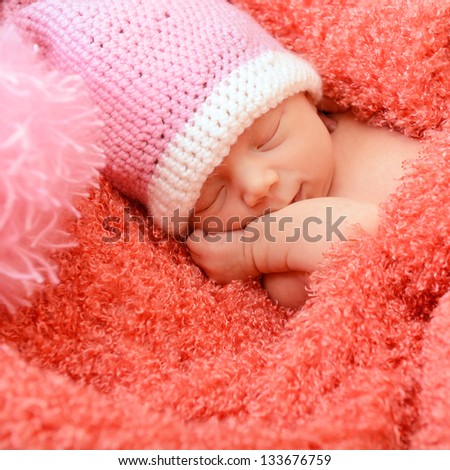 sleeping cute baby funny pink hat in soft fabric and smiling in sweet dreams, beautiful kid's face closeup