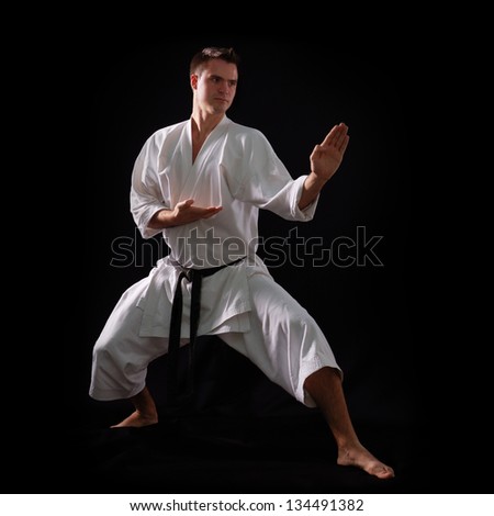 karate man with black belt posing, champion of the world on black background studio shot