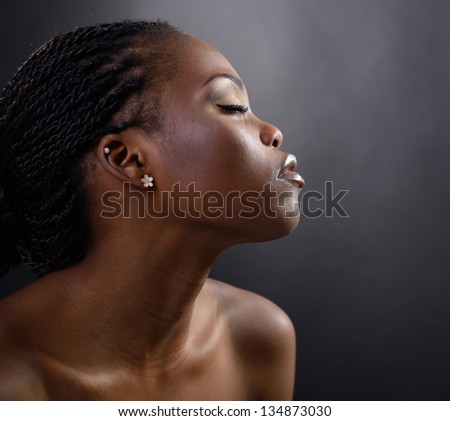 Profile of young attractive african woman, over dark studio background