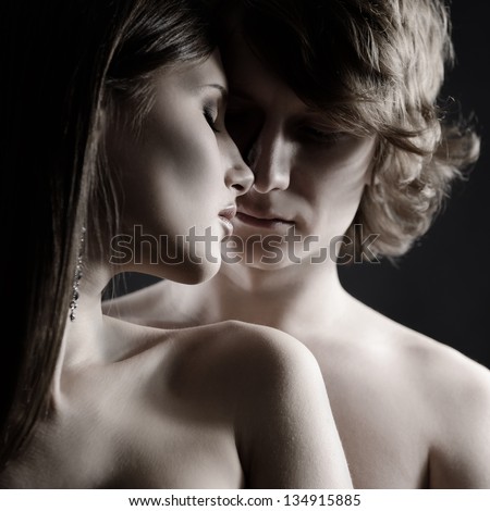 Sexy passion couple, beautiful young man and woman in love closeup, studio shot over black