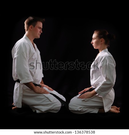 fighting karate couple, man and woman with black belts - champions of the world, on black background studio shot