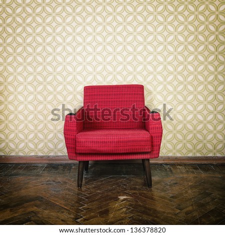 Vintage room with old fashioned red armchair, wallpaper and weathered wooden parquet floor