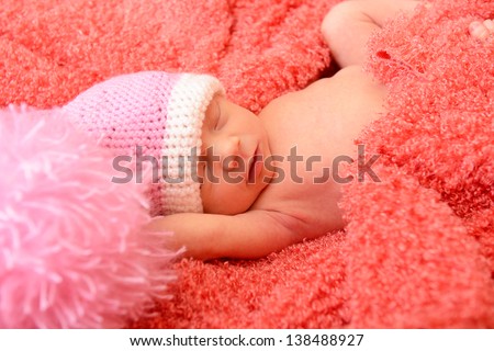 sleeping cute baby funny pink hat in soft fabric and smiling in sweet dreams, beautiful kid\'s face closeup