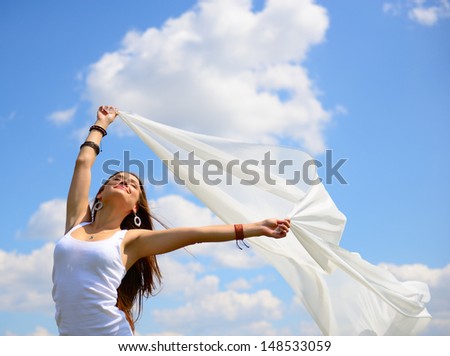 Happy Young Woman Holding White Scarf With Opened Arms Expressing Freedom, Outdoor Shot Against Blue Sky