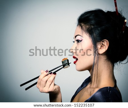 Young Beautiful Asian Woman Eating Sushi With Chopsticks, Toned Image And Noise Added
