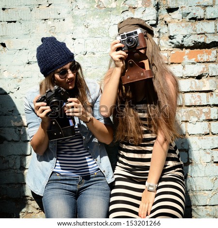 urban girls have fun with vintage photo cameras outdoor near grunge wall image toned and noise added urban girls have fun with vintage photo cameras outdoor near grunge wall image toned and noise added