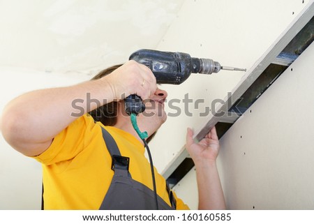 Man using drill to attach drywall panel to wall. Work with plasterboard
