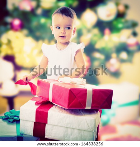 Holidays, baby girl opening box with presents, christmas, birthday, new year, x-mas concept - happy child girl with gift boxes
