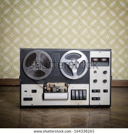 Old Portable Reel To Reel Tube Tape-Recorder Is On Obsolete Parquet In Retro Room With Vintage Wallpaper. Toned