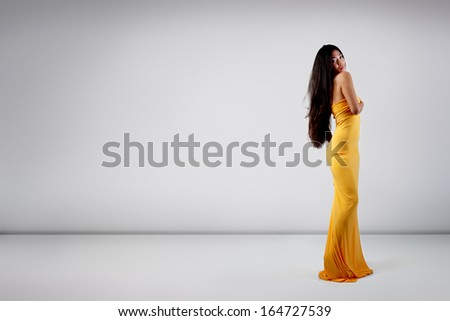 Perfect sexy young woman with perfect body in yellow fabric posing at studio