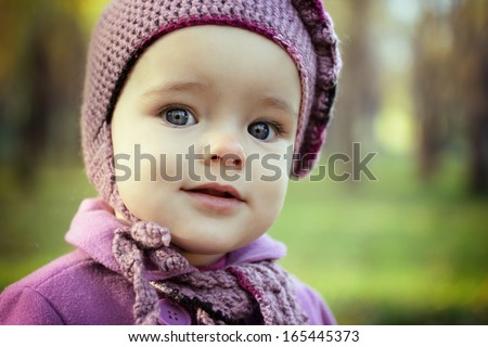 Portrait of cute little girl playing in autumn park. Baby face closeup overnature outdoor.