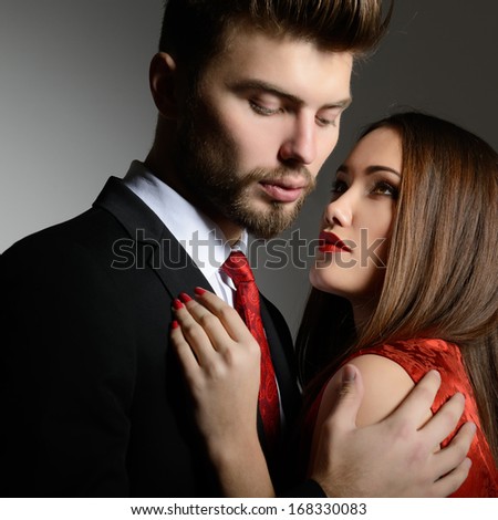 Portrait of beautiful young man and woman dressed in classic clothes, studio shot over grey background. Sexy passion couple in love.