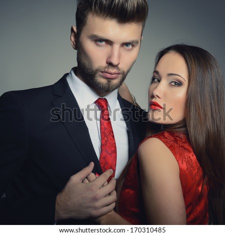 Sexy passion couple in love. Portrait of beautiful young man and woman dressed in classic clothes, studio shot over grey background
