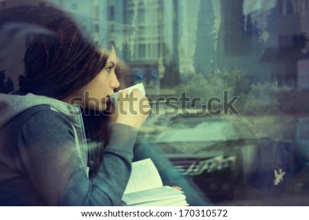 Young Woman Drinking Coffee And Reading Book Sitting Indoor In Urban Cafe. Cafe City Lifestyle. Casual Portrait Of Teenager Girl. Toned.