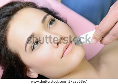 beautiful face of young woman and rejuvenated treatment, lady lies on a couch in a beauty spa getting electrostimulation lifting therapy