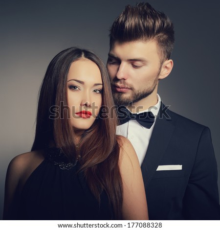Sexy passion couple in love. Portrait of beautiful young man and woman dressed in classic clothes, studio shot over grey background