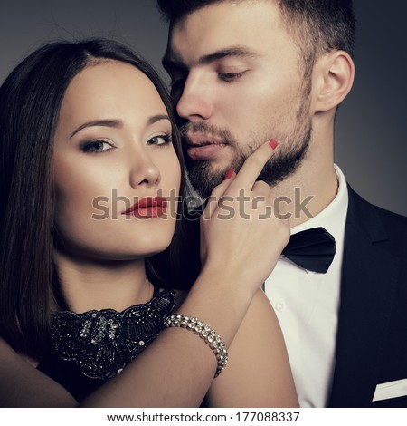 Sexy passion couple in love. Portrait of beautiful young man and woman dressed in classic clothes, studio shot over grey background