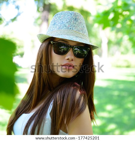 young beautiful lady outdoor portrait, girl in summer park  in sunglasses and fedora with long brown hair