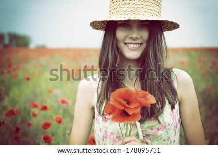 Young beautiful happy woman in straw hat on a poppy field, summer outdoor.