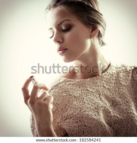 Girl with perfume, young beautiful woman holding bottle of perfume and smelling aroma, toned