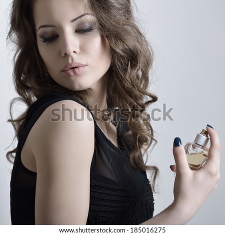 Girl with perfume, young beautiful woman holding bottle of perfume and smelling aroma, toned.