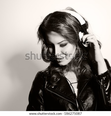 Young beautiful woman with headphones listening music. Teenager girl and music concept. Black and white toned.
